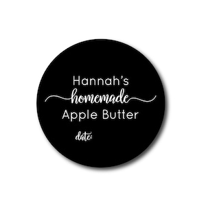 May include: A round, black label with white text. The label reads "Hannah's homemade Apple Butter" in a script font, with the word "homemade" in cursive. Below, the word "date:" is printed.