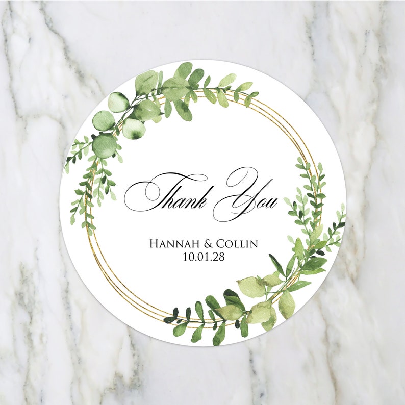 Pode incluir: Etiqueta redonda branca de agradecimento com um c&iacute;rculo dourado e folhas verdes de aquarela. O texto diz "Obrigado" com os nomes "Hannah & Collin" e a data "10.01.28" abaixo.