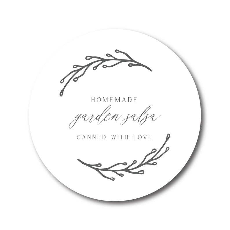 May include: A round white label with the text "HOMEMADE garden salsa CANNED WITH LOVE" in a script font. The label is bordered by a gray floral design. The label is for homemade salsa.