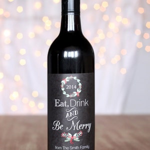 May include: A black wine bottle with a black and white label that says "Eat, Drink and Be Merry" with a green wreath and red bow. The label also says "from The Smith Family" and "2014".