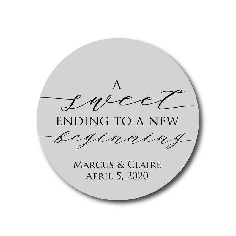 May include: A round, gray sticker with the text "A sweet ending to a new beginning" in black cursive font. Below the text is "Marcus & Claire April 5, 2020" in black sans-serif font.