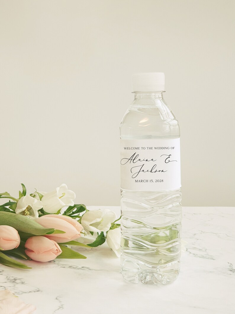 May include: A clear plastic water bottle with a white label that says "Welcome to the wedding of Alaina & Jackson March 15, 2028".