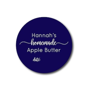 May include: A round, navy blue label with white text. The label reads "Hannah's homemade Apple Butter" in a script font, with "date:" below. The label is designed for homemade food products.