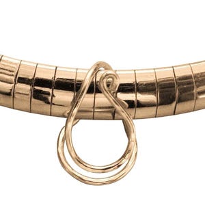 May include: A gold-toned omega chain necklace featuring a polished, curved, segmented band. A singular, teardrop-shaped pendant made of thin, looped gold-toned wire is suspended from the center of the chain, creating a continuous, fluid design.