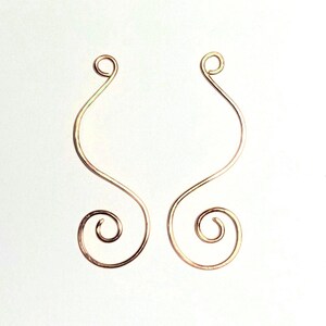 May include: Two copper-colored wire components shaped into elongated S-curves. Each piece features a small circular loop at the top and a larger, tighter spiral at the bottom, crafted from a single continuous length of metallic wire.