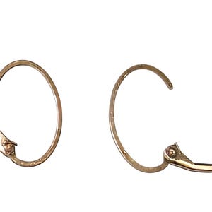 May include: Two gold-colored hoop earrings with a lever back closure. The earrings are circular with a small, decorative element near the closure. The lever back is open on one earring.