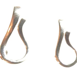 May include: A pair of silver-toned metal earrings, each featuring an open, teardrop-shaped loop design with a curved, overlapping top section. The earrings have a smooth, reflective surface and a continuous, fluid form that creates a hollow center.