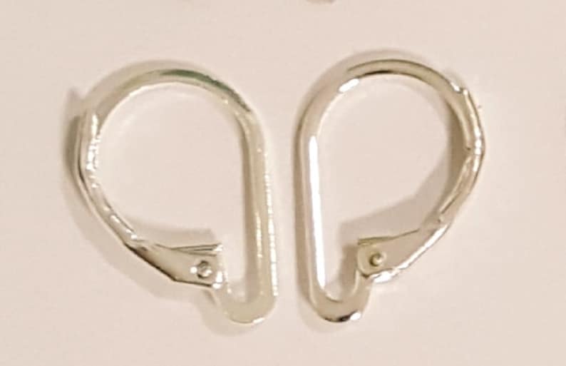 May include: Two silver-colored leverback earring findings. Each finding has a curved, U-shaped design with a hinged lever closure. The findings are made of a shiny, metallic material and are set against a light background.