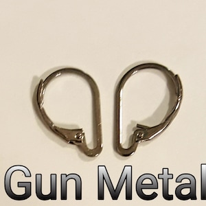 May include: Two gunmetal-colored leverback earring findings. The findings are made of metal and have a curved, hinged design. The text "Gun Metal" is displayed in a gradient font below the earrings.
