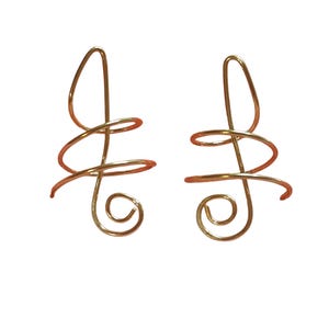 May include: A pair of gold-toned metal earrings featuring a continuous wire design. Each earring is shaped into a series of interconnected loops and spirals, forming an abstract, elongated silhouette with a polished, reflective surface finish.