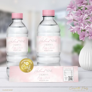 May include: Two clear water bottles with pink caps and labels that read "Cloud Nine, Lauren's Baby Shower, August 17, 2024." A matching label and a vase of pink flowers are also visible.