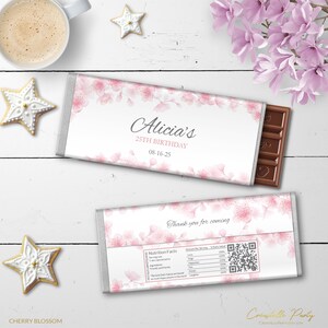 May include: A white chocolate bar wrapper with a pink cherry blossom design. The wrapper has the text "Alicia's 25th Birthday 08-16-25" and "Thank you for coming".
