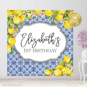 May include: A blue and white tiled backdrop with lemons and flowers. The text "Elizabeth's 1st Birthday" is in a gold frame.