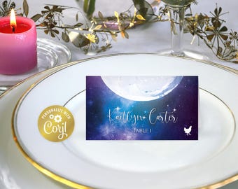 May include: A purple and blue space-themed table card with a white moon and stars. The text on the card reads "Kaitlyn Carter Table 1".
