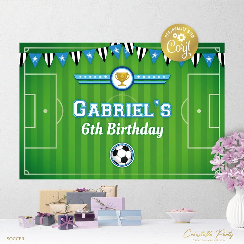 May include: A green and white soccer field backdrop with blue and black pennants. The backdrop has a soccer ball, a trophy, and the text "Gabriel's 6th Birthday".