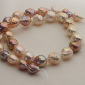 May include: A strand of baroque pearls in shades of pink and white. The pearls are strung on a white thread and have an iridescent sheen.
