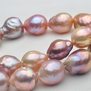 Op de afbeelding: Een streng barokparels met iriserende roze, perzik en lavendel tinten. De parels zijn onregelmatig van vorm en hebben een natuurlijke, organische uitstraling.