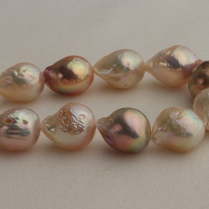 May include: A strand of baroque pearls with a pink and white iridescent sheen. The pearls are irregular in shape and have a natural, organic look.