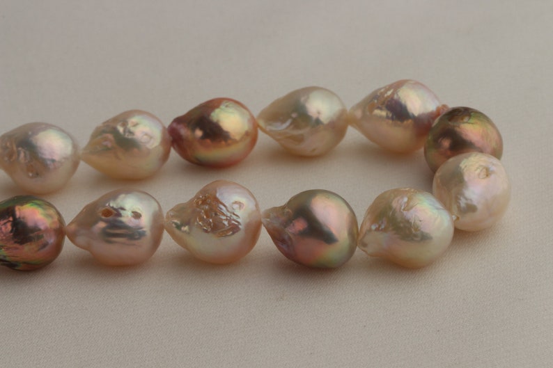 May include: A strand of baroque pearls with a pink and white iridescent sheen. The pearls are irregular in shape and have a natural, organic look.