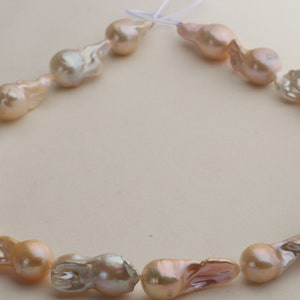 May include: A strand of baroque pearls in shades of pink and white. The pearls are irregular in shape and have a natural luster.