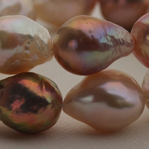 May include: A strand of iridescent pink and white baroque pearls. The pearls are irregular in shape and have a smooth, glossy finish.