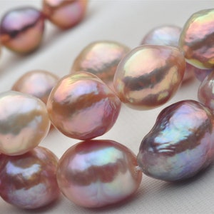 Op de afbeelding: Een streng barokparels met iriserende roze, perzik en lavendel tinten. De parels zijn onregelmatig van vorm en hebben een gladde, glanzende afwerking.