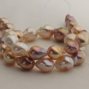 May include: A strand of iridescent pink and white baroque pearls, strung on a white thread.
