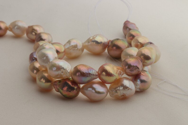 May include: A strand of iridescent pink and white baroque pearls, strung on a white thread.