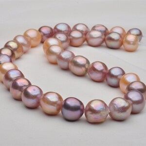 May include: A strand of pink and peach freshwater pearls. The pearls are round and have a slight iridescent sheen.