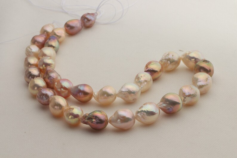 May include: A strand of baroque pearls in shades of pink and white. The pearls are irregular in shape and have a lustrous sheen.