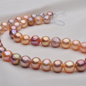 May include: A strand of pink and peach freshwater pearls, strung on a white cord. The pearls are round and have a slight iridescent sheen.