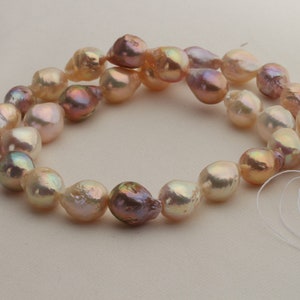May include: A strand of baroque pearls with a mix of peach, pink, and iridescent colors. The pearls are strung on a white thread and have a natural, irregular shape.