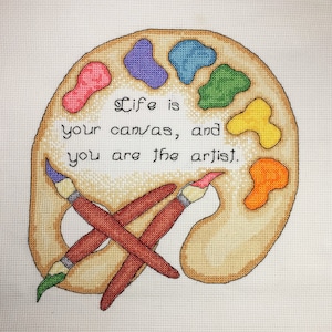 May include: A brown and beige paint palette with colorful paint swatches and two paintbrushes crossed over the palette. The text "Life is your canvas, and you are the artist." is written on the palette.