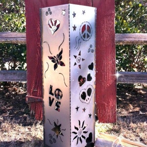 Pode incluir: Uma lareira de metal prateada com recortes de sinais de paz, cora&ccedil;&otilde;es, estrelas e a palavra "LOVE".