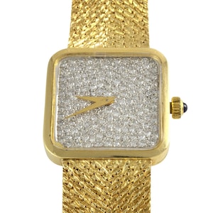 以下が含まれることがあります： 正方形の文字盤とダイヤモンドで覆われたダイヤルを持つ金の腕時計。時計は金色のメッシュバンドです。