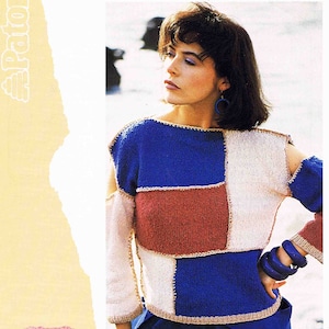 May include: A woman wearing a multi-colored knitted sweater with a blue, white, and red color scheme. The sweater has a square pattern and a scoop neck. The woman is wearing blue pants and has her hair pulled back. The image includes a ball of pink yarn with the text "Patons Cotton Top" on the label. The text "66-97 cm 26-38 in CODE B 7562 Includes Childs & Teens sizes" is also visible in the image.