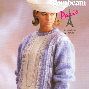 May include: A light purple and white knitted sweater with a cable knit design. The sweater is worn by a woman with a white hat and a silver necklace. The text "922 Sunbeam Paris" is printed on the image. The text "81-102 cm 32-40 ins" is also printed on the image.