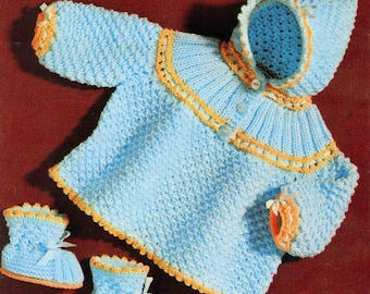 May include: A light blue knitted baby outfit with a matching hooded jacket and booties. The jacket and booties are trimmed with orange yarn. The outfit is displayed on a red background. The image includes the text "Sirdar" and "Snuggly Baby Yarns".
