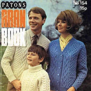 Puede incluir: Una portada de libro de patrones de tejido vintage con una familia usando suéteres Aran. El libro se titula "Patons Aran Book" y tiene el número "No 154 15p" impreso en la portada. El texto "12 Designs for the family in Capstan" está impreso en la parte inferior de la portada.