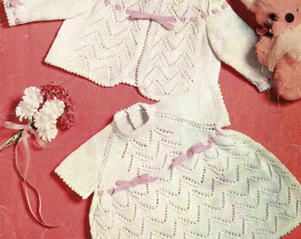 May include: A vintage baby clothing set, including a jacket and dress, in white with pink ribbon accents. The knitted garments feature a chevron pattern and are designed for a chest size of 18-19 inches. The image also includes text that reads "PATONS Brilliante 3 ply".