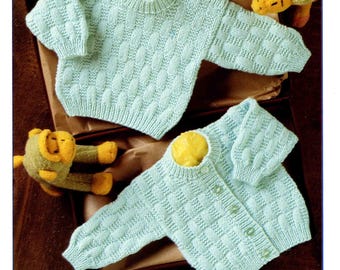 May include: A light blue knitted baby sweater and cardigan set with a textured pattern. The set includes a crew neck sweater and a button-up cardigan. The image also shows two stuffed animal toys. The text "BABY D.K." and "4649" are visible.