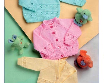 May include: Image of baby sweaters in light blue, pink, and yellow. The sweaters have decorative patterns and button closures. The image also includes small stuffed animal toys. The text "Wondersoft DK" and "Stylecraft" are visible.