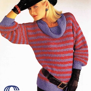 May include: A red and purple striped sweater with a cowl neck and a black belt. The sweater is made with a textured yarn and has a loose fit. The model is wearing a black hat and gloves.
