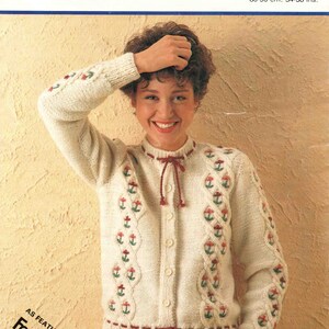 May include: A white cardigan with a cable knit pattern and floral embroidery. The cardigan has a tie at the neck and buttons down the front. The cardigan is 34-38 inches in size.