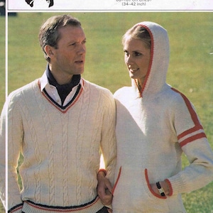 May include: A white knitted sweater with a v-neck and cable knit design. The sweater has a red, white, and blue trim around the neck and bottom. The sweater is being worn by a person standing in a grassy field. The text "DOUBLE KNITTING" and "898" is visible in the image.
