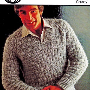 Puede incluir: Un suéter gris tejido con un patrón de punto de cable. El suéter tiene cuello en V y mangas largas. El suéter está hecho de hilo grueso. La imagen incluye el texto "B 6331 34-44" y "Chunky".