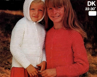 Könnte beinhalten: Vintage Strickmuster-Cover mit zwei Kindern. Ein Kind trägt eine weiße Kapuzenstrickjacke und eine rote Hose, das andere eine rote Strickjacke. Der Text "SIRDAR" steht oben, darunter "DK 22-30".