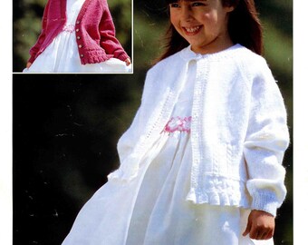 Könnte beinhalten: Ein junges Mädchen in einem weißen Kleid und einem weißen Strickcardigan. Der Cardigan hat einen Knopfverschluss und einen Rüschensaum. Ein kleineres Bild zeigt das Mädchen in einem rosa Cardigan. Der Text "LEGEND 4 PLY" und "SIRDAR" sind sichtbar.