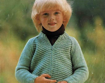 May include: A vintage knitting pattern cover featuring a child wearing a light green knitted sweater with a zipper. The sweater is paired with a dark turtleneck. The text "Patons Beehive" is displayed at the top, with measurements of 22-28 inches.