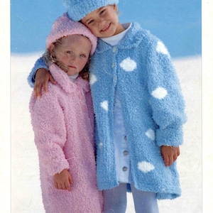 May include: Two children wearing matching knitted coats and hats. One coat is light blue with white cloud-shaped accents, the other is pink. The image has the word "SNOWFLAKE" at the top and "SIRDAR" at the bottom.